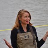 Melanie Stansbury in overalls wading in the Rio Grande.