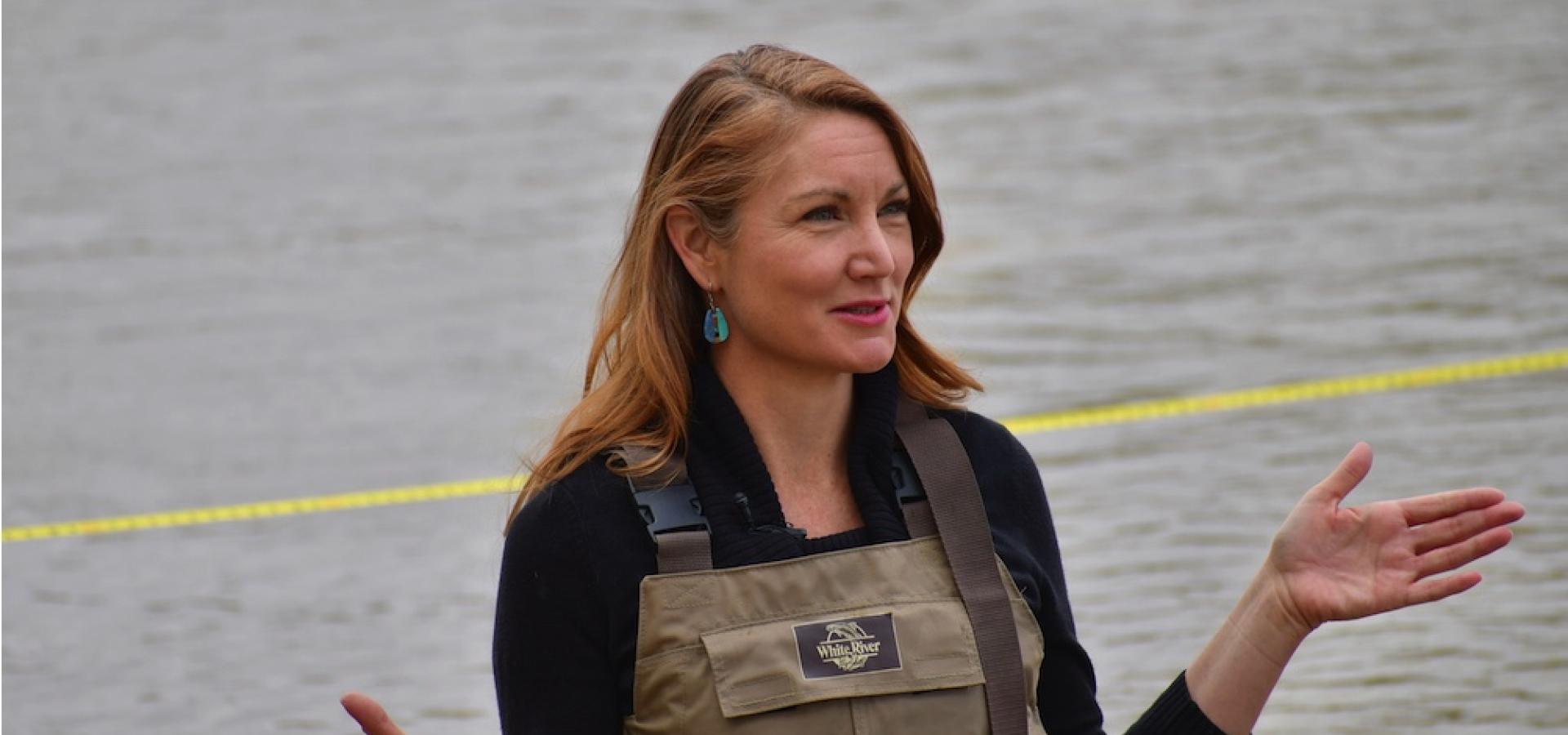 Melanie Stansbury in overalls wading in the Rio Grande.
